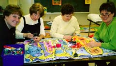 Teachers bind the edges of the first mural made into a quilt sandwich. Susan Shie 2001.
